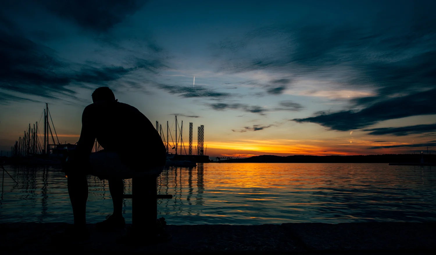 Silhouette sunset sea water man sitting pier – Landscape