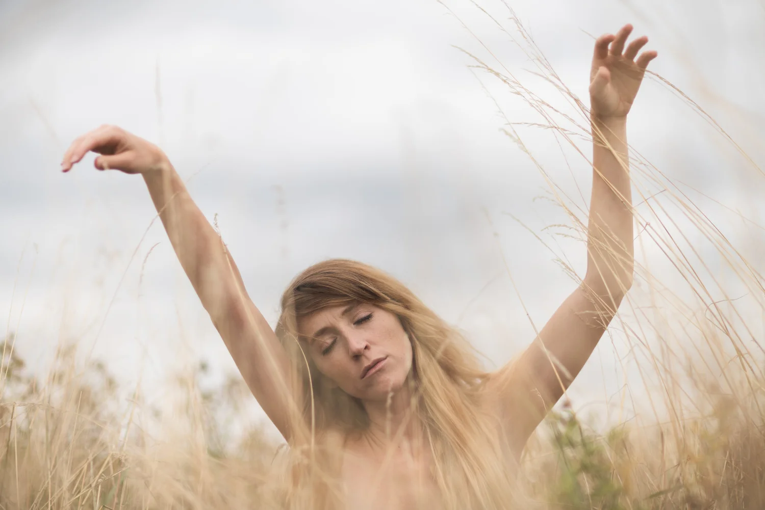 Woman field arms raised summer grass blonde – Portrait