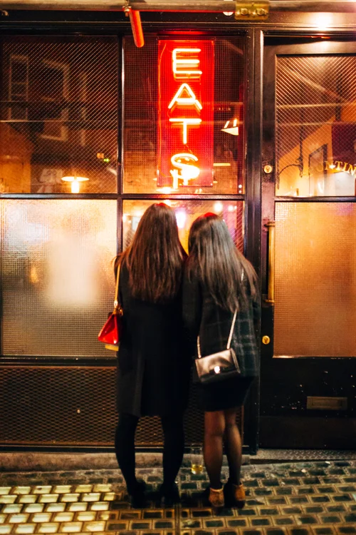 Eats neon sign night two women street – Street