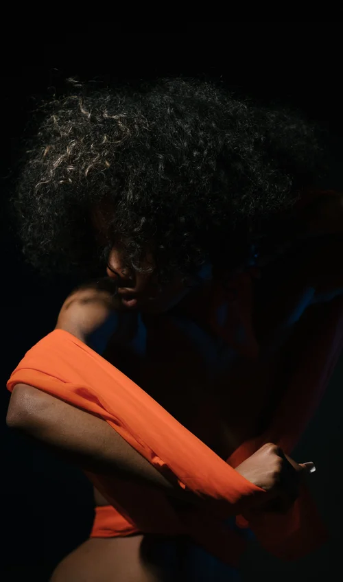 Woman afro orange top studio dark fashion – Fashion & Portrait Photography